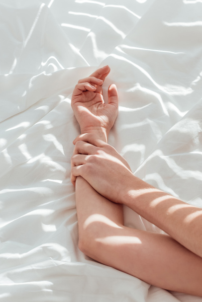 cropped shot of loving couple lying on white bed sheet together - Valokuva, kuva