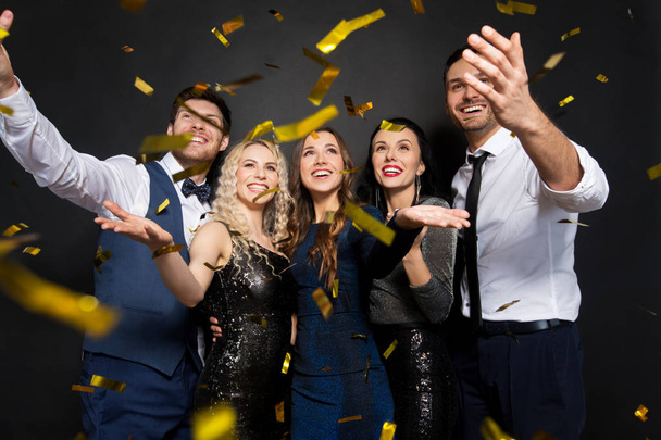 happy friends at party under confetti over black - Foto, Bild