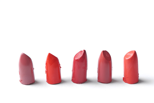 close up view of cut lipsticks on different colors on white backdrop - Photo, Image