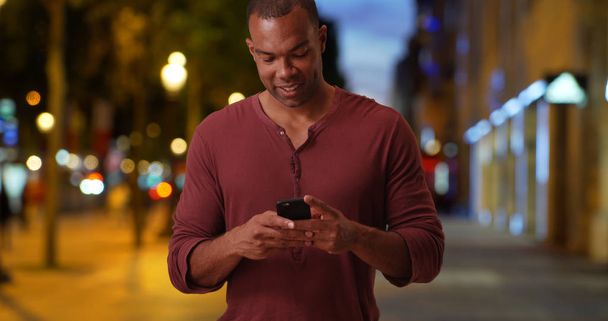 Hombre africano casual en Campos Elíseos en París Francia envía texto con teléfono inteligente
 - Foto, imagen