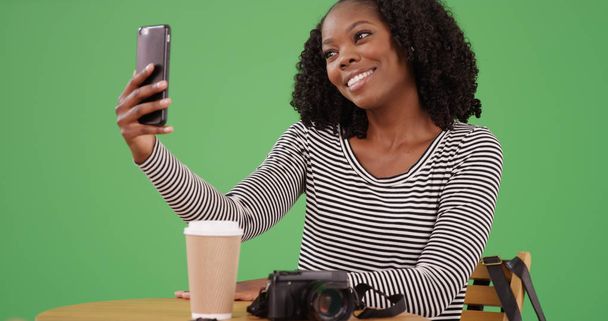 Piękna młoda kobieta czarny biorąc selfie z telefonu w kawiarni na zielony ekran - Zdjęcie, obraz