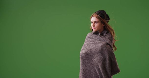 Young woman wrapped up in blanket standing on green screen - Zdjęcie, obraz
