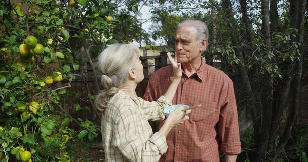 Senior couple standing eating in garden - Photo, Image