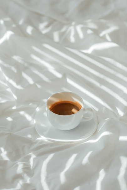 close up view of cup of coffee on white bed sheet - Φωτογραφία, εικόνα