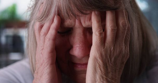 Tight shot de anciana mujer caucásica con migraña dolor de cabeza en el día lluvioso
 - Foto, imagen