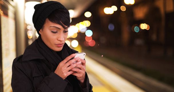 Woman on urban city subway metro platform at night texting on smartphone - Photo, Image