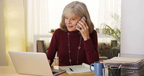 Mature woman talking smartphone laptop computer - Photo, image