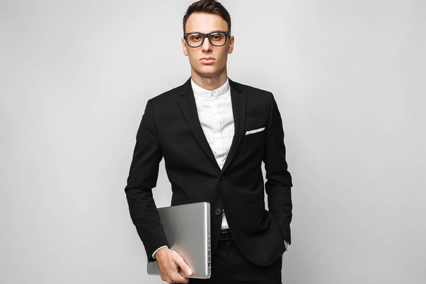 Business man in suit and glasses with laptop isolated on gray background. Business concept - Zdjęcie, obraz