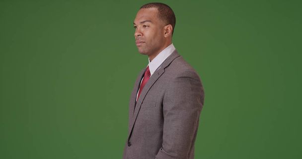 Een zwarte zakenman kijkt vol vertrouwen uit op groen scherm - Foto, afbeelding