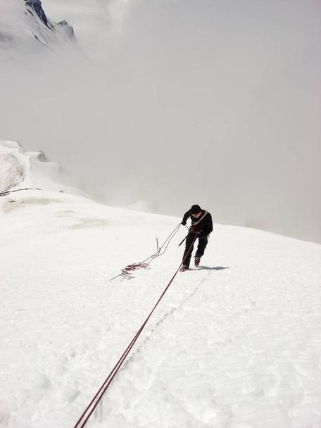 mountain climber rappelling off s steep snowy mountain peak in the Swiss Alps above Zermatt - Photo, Image