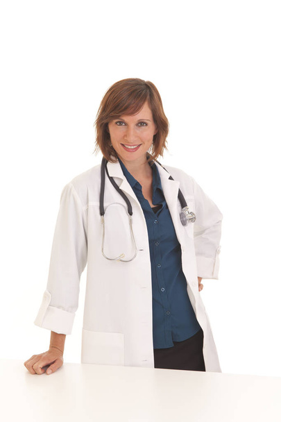 Портрет молодой женщины-врача, опирающейся на стол в белом халате
 - Фото, изображение
