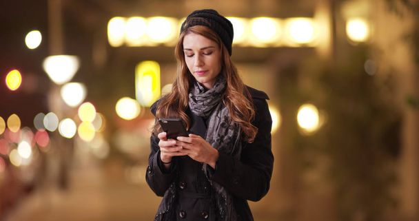 Jeune femme millénaire en utilisant smartphone à l'extérieur la nuit
 - Photo, image