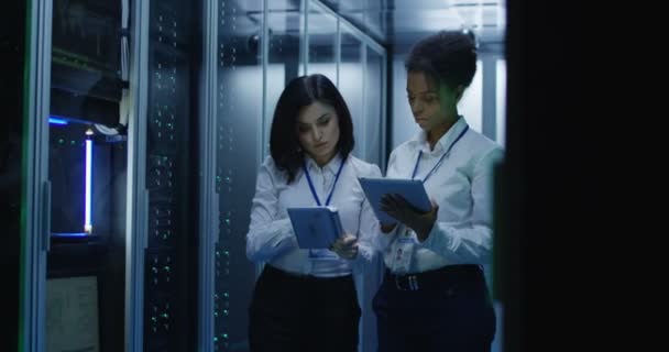 Duas mulheres estão trabalhando em um data center com linhas de racks de servidores
 - Filmagem, Vídeo