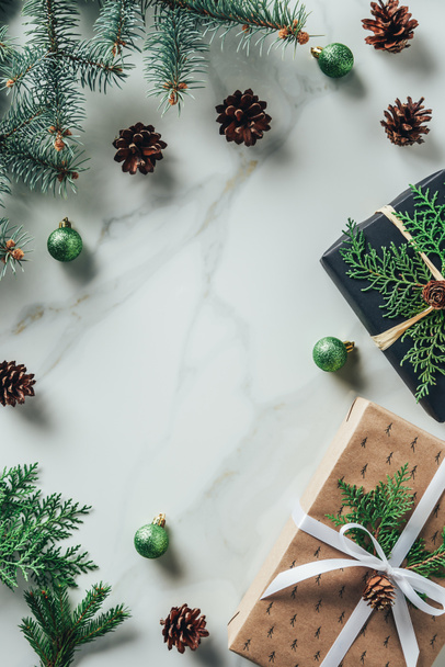 vista superior de las cajas de regalo de Navidad con ramas de abeto y conos de pino sobre fondo de mármol con espacio de copia
 - Foto, Imagen