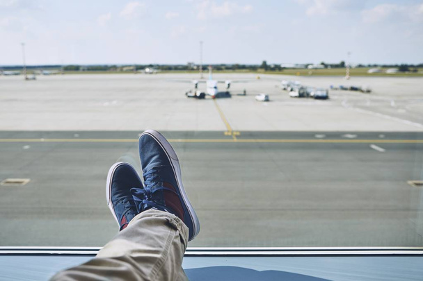 Man waiting at airport. Personal perspective of traveler from window to taxiways and runway. - Zdjęcie, obraz