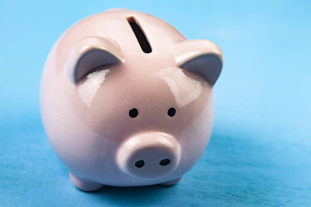 Pink pig money box on blue wooden background close up. - Foto, imagen