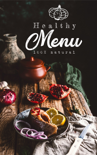 Baked salmon steak with lemon and onion on plate with pomegranate on wooden table, healthy menu lettering - Foto, afbeelding