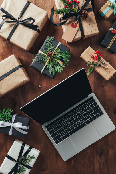 top view of christmas presents and laptop with blank screen on wooden background - Photo, Image