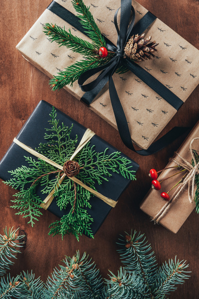 вид зверху різдвяні подарункові коробки з ялинковими гілками та сосновими шишками на дерев'яному фоні
   - Фото, зображення