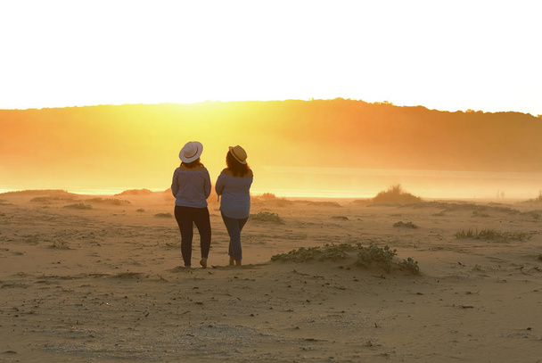 It was a stunning sunset at the mouth of the Kleinbrak River. No wind and no breeze. This two young friends enjoy the last moments of the day before sunset on the beach. - Foto, Imagen