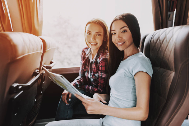 Young Beautiful Smiling Women Holding Paper Map. Casualy dressed Happy Travelers Planning Route Together by Looking at Map. Traveling, Tourism and Friendship Concept. Summer Vacation - 写真・画像