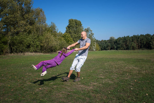 Een vader en dochter spelen in het park op een zonnige dag. - Foto, afbeelding