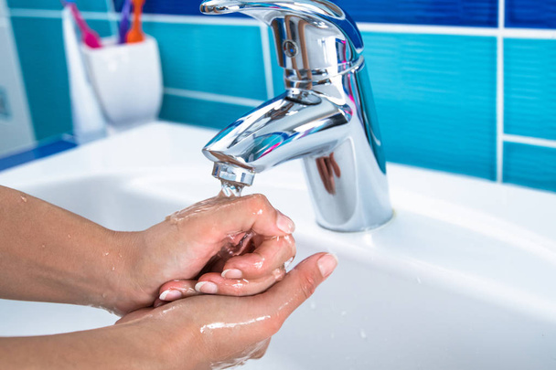 Femme nettoie ses mains dans la salle de bain
. - Photo, image
