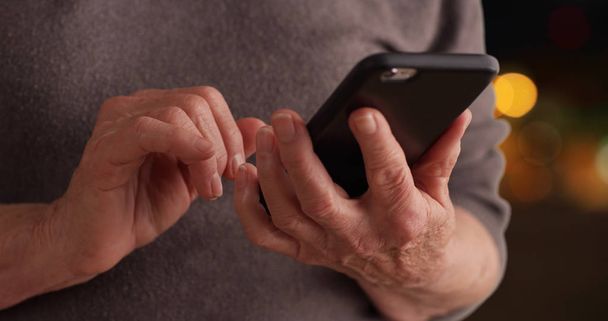 Olgun kadın bokeh arka plan üzerinde mesajları okumak için smartphone kullanarak Close-up - Fotoğraf, Görsel