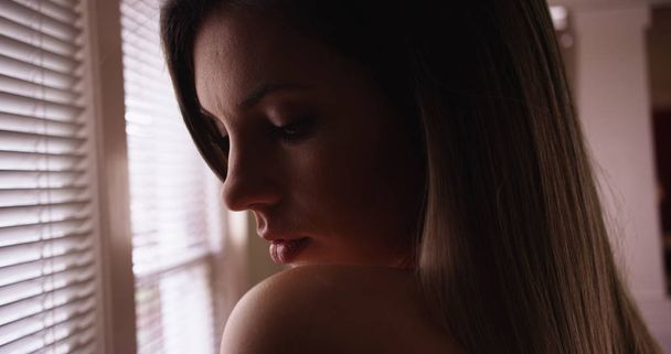 Millennial donna nel suo 20s bagnato in ombra guardando drammatico all'interno dalla finestra
 - Foto, immagini
