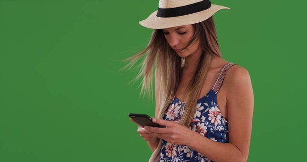 Frau in geblümtem Strampler und Fedora-SMS auf Handy auf Greenscreen - Foto, Bild