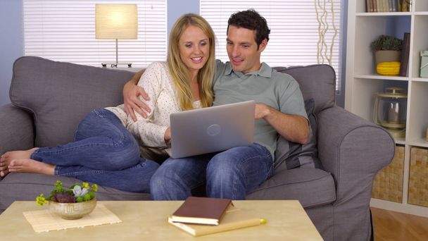Makea pari käyttää kannettavaa tietokonetta sohvalla
 - Valokuva, kuva