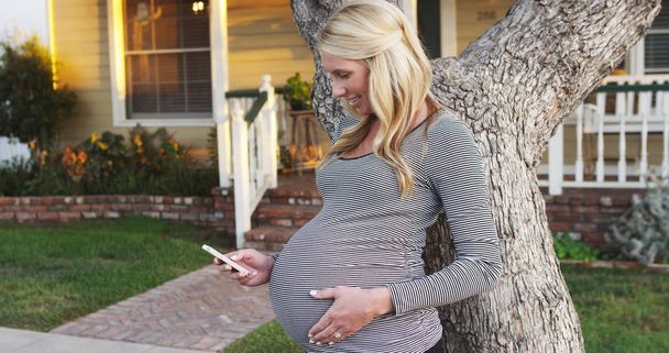 Feliz mulher grávida mensagens de texto no smartphone ao ar livre
 - Foto, Imagem