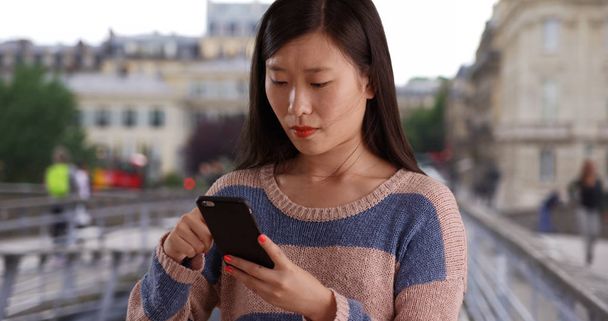 Close up of cute woman using cell phone and sending texts in Paris France - Photo, Image
