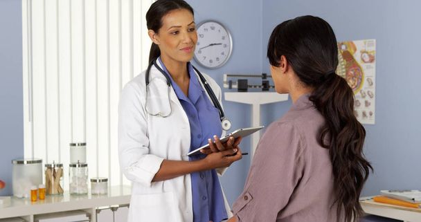 Afryki amerykański ginekolog mówi do pacjenta z tabletu - Zdjęcie, obraz