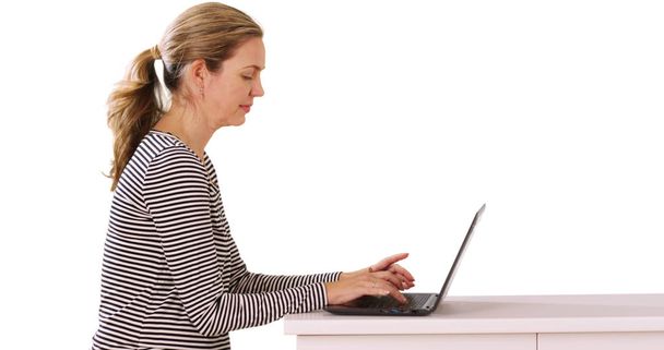 Perfil da mulher caucasiana sentada à mesa trabalhando no laptop
  - Foto, Imagem