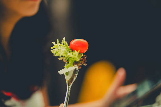gemischter Salat auf Gabel auf unscharfem Restaurant-Hintergrund. - Foto, Bild