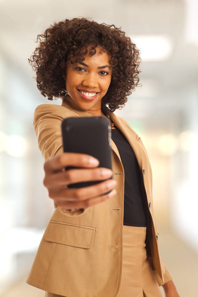 Preciosa empresaria milenaria tomando selfie con cámara de teléfono inteligente en el trabajo
 - Foto, imagen