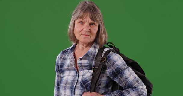 Érett stern kaukázusi nő pózol hátizsák állt a zöld képernyő - Fotó, kép