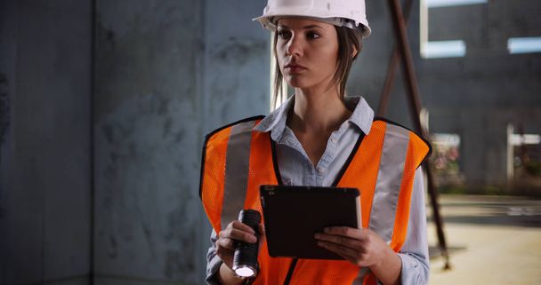 Женщина-инженер работает и светит фонариком на камеру на стройке
 - Фото, изображение