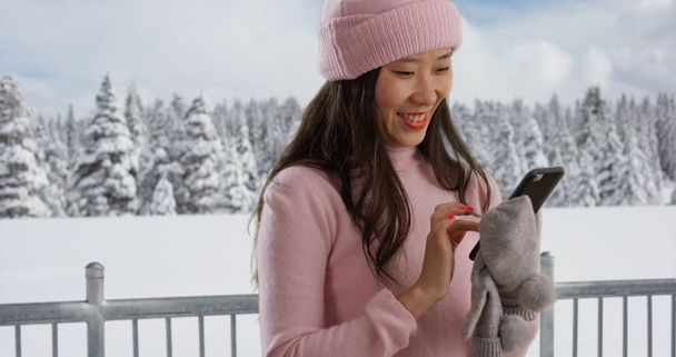 Feliz joven mujer sonriendo y usando smartphone en el parque cubierto de nieve
 - Foto, imagen