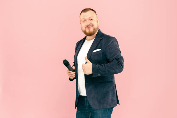 Young man with microphone on pink background, leading with microphone - Foto, Bild