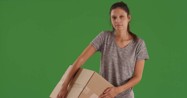 Brunette woman standing carrying large cardboard box on green screen - Zdjęcie, obraz