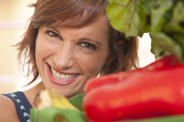 Εσωτερικη πορτρέτο της νεαρής γυναίκας χαμογελαστά με λαχανικά - Φωτογραφία, εικόνα
