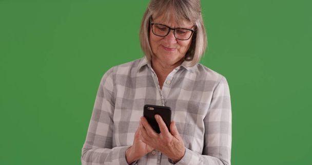 緑色の画面でモバイル デバイスを使用して成熟した白人女性 - 写真・画像