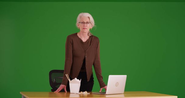 Volwassen zakenvrouw in pauze kamer met Chinees eten en laptop op groen scherm - Foto, afbeelding