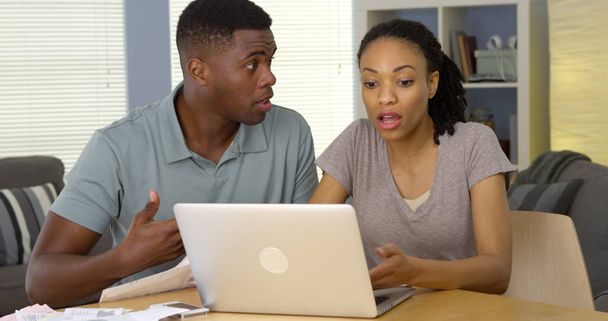 Verärgertes schwarzes Paar streitet mit Laptop um Rechnungen und Finanzen - Foto, Bild