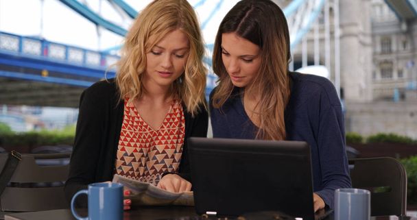 Due belle ragazze guardando la mappa e laptop vicino punto di riferimento nel Regno Unito
 - Foto, immagini