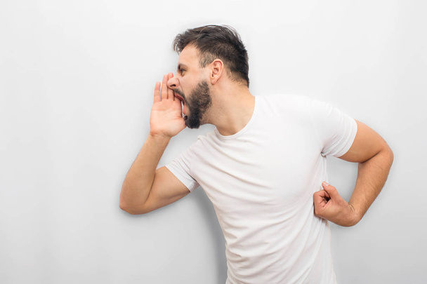 Emotional man expressing his feelings. He screams and yells. Guy coveres mouth with hand from one side. Isolated on white background. - Foto, immagini