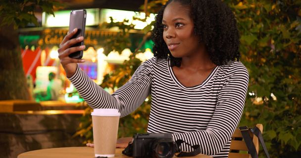Linda mujer negra toma una selfie con teléfono inteligente cerca de puesto de comida en la noche
 - Foto, imagen