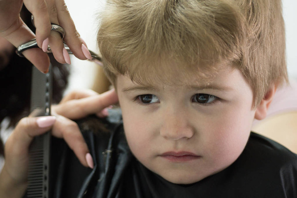 Making the haircut experience enjoyable. Little child given haircut. Small child in hairdressing salon. Little boy with blond hair at hairdresser. Cute boys hairstyle. Hair salon for kids. Hair ideas - Photo, Image